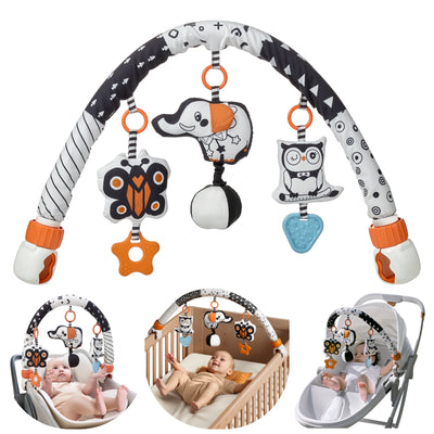 A colorful baby activity arch toy featuring black, white, and orange high-contrast patterns. The arch has three plush hanging toys: a butterfly with orange and white accents, an elephant with an orange ear, and an owl with glasses and a bow tie. Each toy is attached with an orange ring, and the butterfly and owl have textured teething shapes hanging below them. The arch is supported by two adjustable clamps with orange twist knobs, designed to attach securely to surfaces like strollers or car seats.