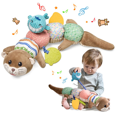Colorful baby sensory toy designed as a plush otter in caterpillar form. The toy features a brown otter head with cute facial details at one end and a tail at the other, with five colorful textured segments in between. Each segment has different patterns and fabrics: pink with small circles, striped, multicolored squares, green with dots, and a blue whale head attachment. Yellow leaf-shaped teethers hang from the toy. 