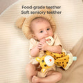 A baby lying on a bed with a bear-shaped pillow, holding and chewing on a food-grade teether attached to a giraffe baby security blanket. The text above says, 