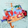 Colorful marine-themed baby cloth book floating in water, featuring cartoon illustrations of a lobster and a crab with 3D textured tails. The book is partially submerged, showcasing its water resistance. Text overlay reads: “Washable and non-fading, skin-friendly and safe,” emphasizing the book’s durability and baby-safe materials.