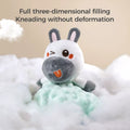 Close-up of a plush animal security blanket lovey with a winking gray and white animal head, orange tongue, and soft mint-green fabric. The toy is shown sitting in fluffy white cotton to highlight fullness. Text above reads: “Full three-dimensional filling. Kneading without deformation.”