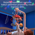 A baby in a crib reaching up toward a rotating crib mobile with plush sea animals and a red crab centerpiece. The mobile projects colorful star-shaped lights on the ceiling and rotates 360 degrees, promoting the baby’s visual tracking and attention skills during nighttime.